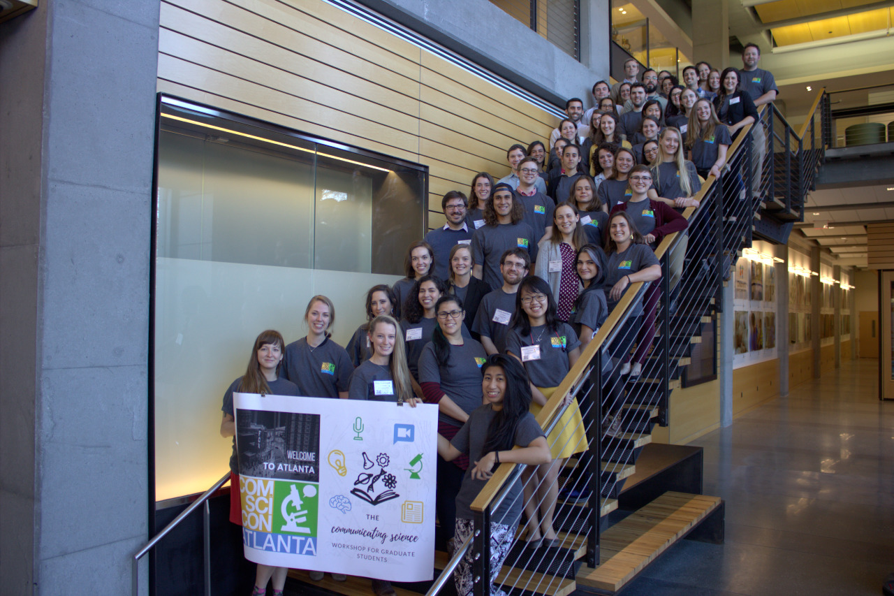 A large group of ComSciCon-Atlanta participants stand smiling on a staircase
