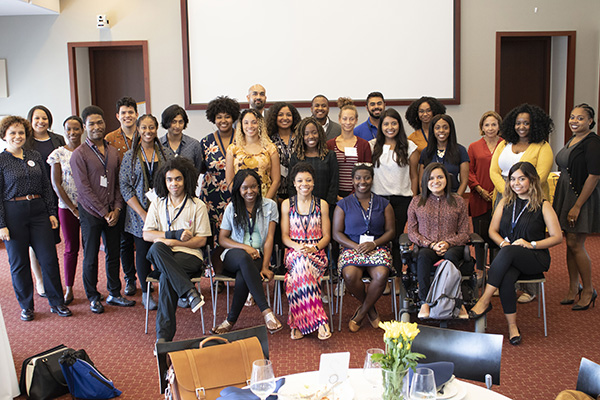 A large, diverse group of 30 students, faculty and staff pose and smile at a reception.