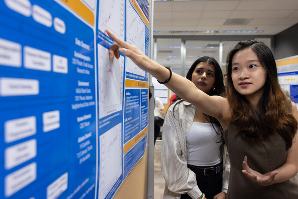 Two graduate students discuss a research poster presentation.