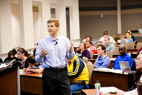 Male faculty member giving lecture to students in a classroom setting.